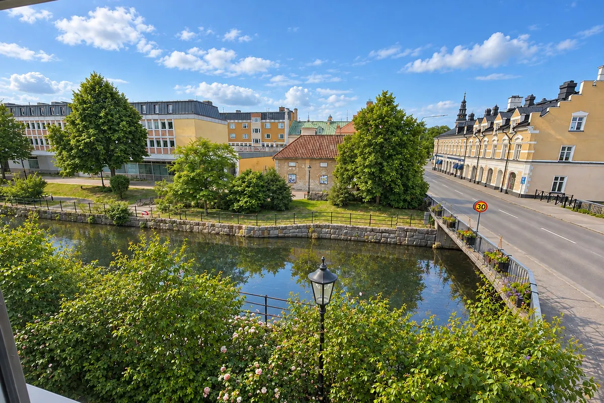 Utsikt över Köpingsån med grönska och gamla trähus i centrala Köping